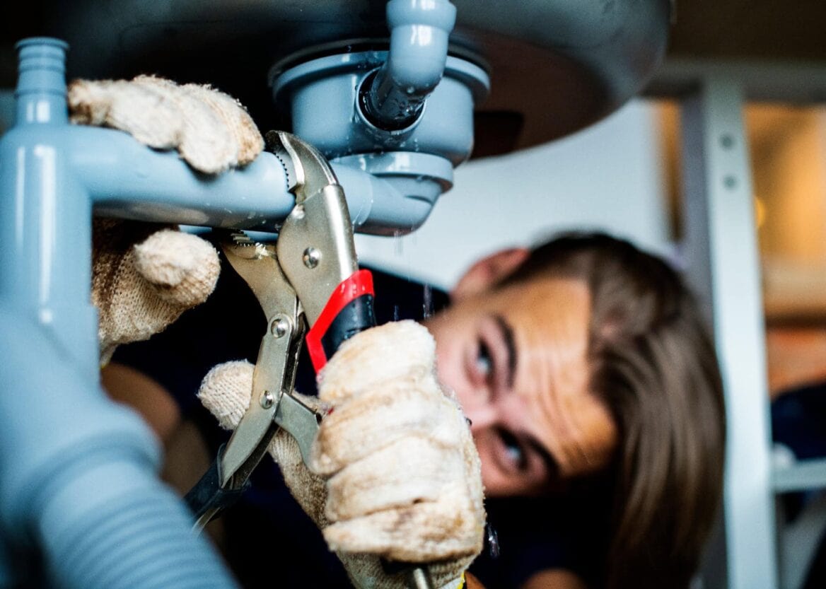 Plumber fixing kitchen sink leak